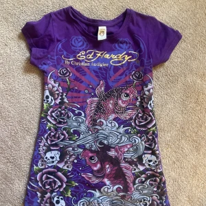 Ed Hardy Tshirt  - En ed heardy tshirt i nyare modell, bra skick. Texten är inte sprucken och de e bara en rhinestone som saknas. Står m på lappen men passar som s/xs
