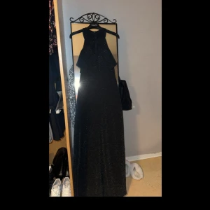 Svart klänning  - Fest/bröllopsklänning  svart glittrig klänning. Jätte fin och skön, lång utan öppningar ganska stretchig men samtidigt tight vid midjan vilket ger en fin figur. Klänningen har bröstkoppar då man behöver inte använda bh. 