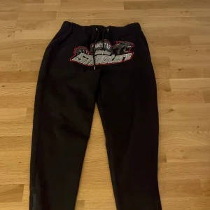 Trapstarbyxor - Ett par svarta mjukisbyxor med ett tryck på framsidan. Byxorna har en elastisk midja med dragsko för justering.