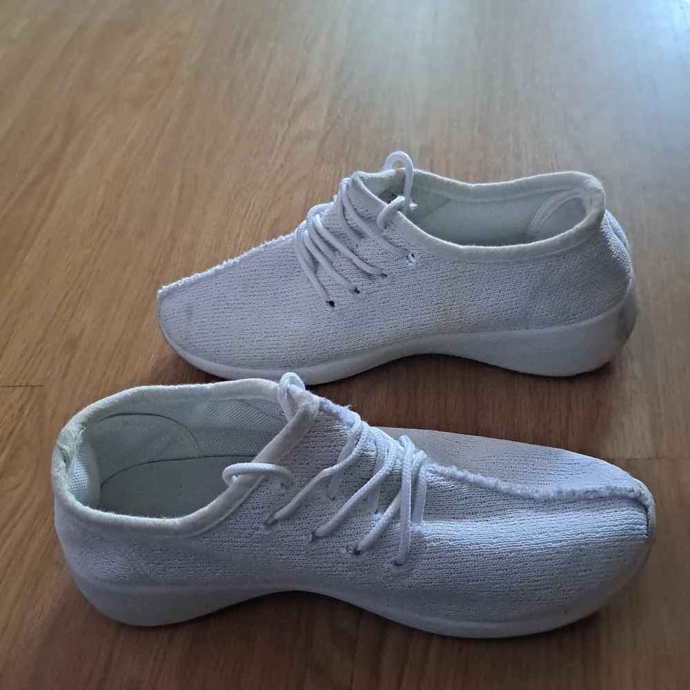 Ett par vita sneakers med snörning. Skorna har en enkel och stilren design med en mjuk ovandel och en bekväm sula.det är lite smudsig men ni kan tvätta den i tvätt maskin. Använd den max 5 gång. fungerar som ny. . Skor.