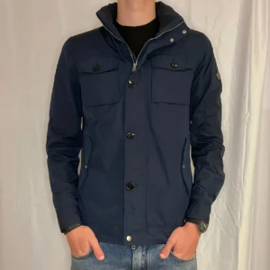 J.Lindeberg Field Jacket  - J.Lindeberg Field Jacket i marinblå färg. Fick i julklapp och den är helt ny. Säljs för att den var för liten. Är helt slutsåld på hemsidan.