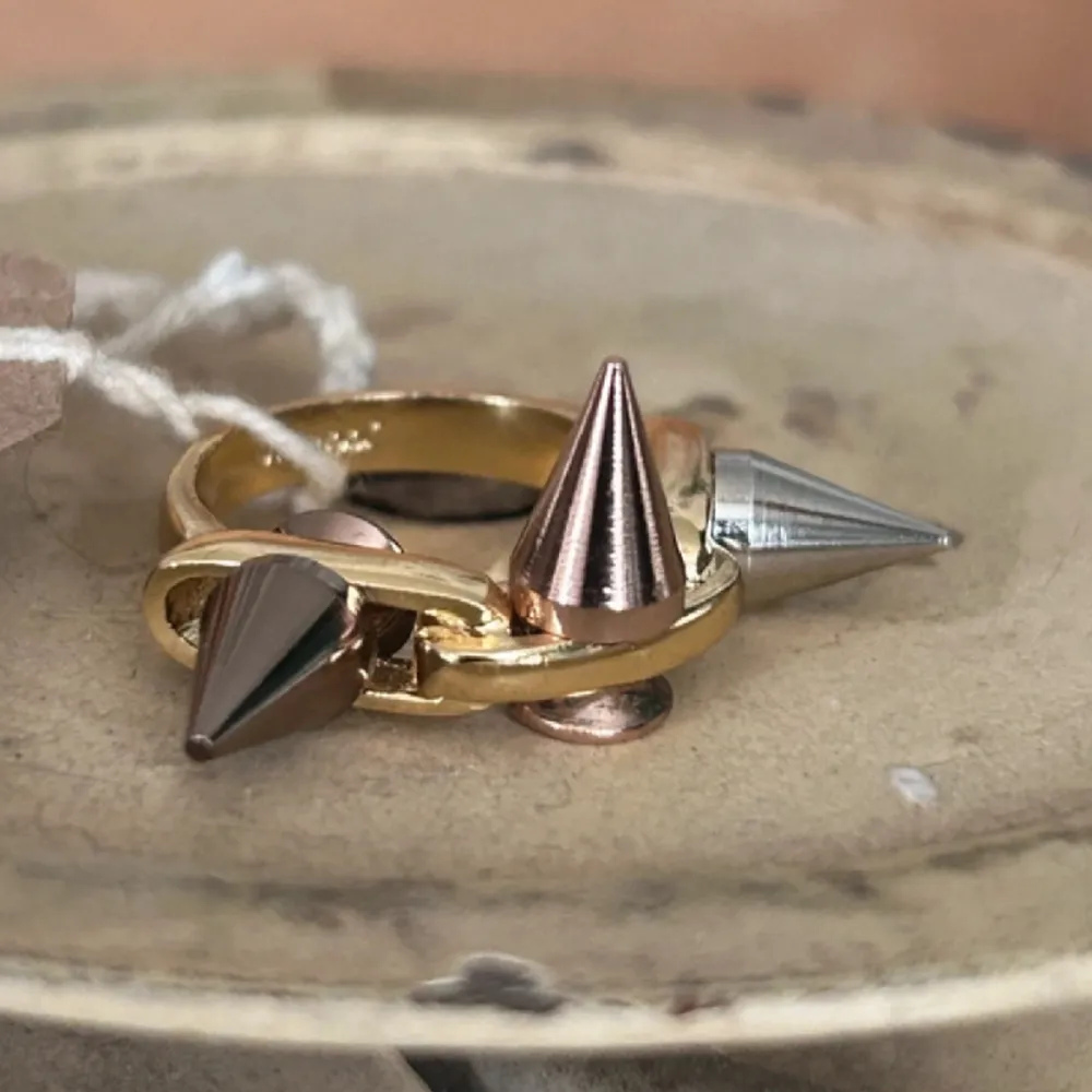 Unik guldfärgad ring från joomi lim med nitar i färgerna silver, brons och rosé. Skulle säga att den passar på långfingret eller tummen. Det är rostfritt stål.. Accessoarer.