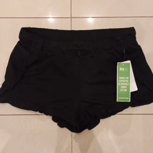 Svarta shorts kappahl - Så söta svarta shorts med volanger från kappahl! 100% bomull Storlek 158/164 De är helt nya och aldrig använda med lapparna kvar.  NYPRIS 149 kr