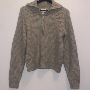 Stickad tröja - Beige stickad tröja med zip-krage. Tröjan kommer från H&M och är i stl xs. (Använt tröjan 1 gång,säljer för den inte passar mig.)
