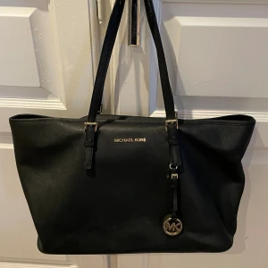 Micheal kors väska  - Super fin äkta Michael kors väska, perfekt till skolan. Skoldator + mappar får plats utmärkt. 3 stora fack & 2 små fack. Lite slitningar på handtagen men inget man tänker på. Svart med guld detaljer💞