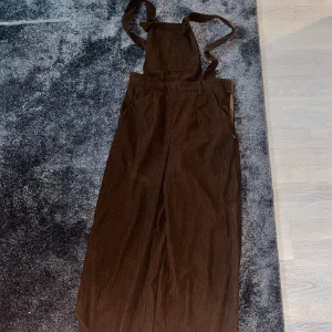 Hängslebyxor  - Snygga mörkbruna hängslebyxor. Kattiga knappt använda och gjordao i manchester