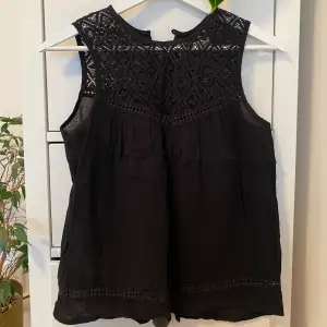 Black coloured top. Thin material. Slightly see through. Back is styled open.