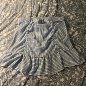 Blå kjol - Det är en tajt blå och vit randig kjol med volang och lite skrunch i bra skick 