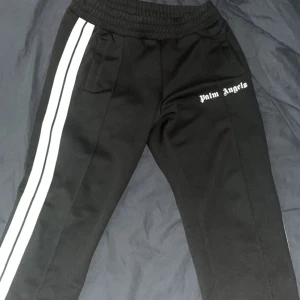 Palm Angels Byxor Svart - Tjena säljer nu mina Palm Angels byxor i färgen svart🌴Självklart äkta och qr kod finns att scanna. Storleken är L men sitter som M. Jag bör vanligtvis M och dessa sitter perfekt på mig. DM för fler frågor samt detaljer!