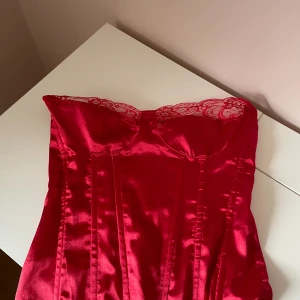 Röd korsett - Röd korsett med dragkedja bak i ryggen. Storlek 34 från prettylittlething. 
