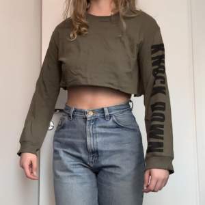 Olivgrön, ångärmad crop top från H&M med svart tryck på ärmen.  - Cool Streetwear stil men tyvärr inte helt min grej längre.