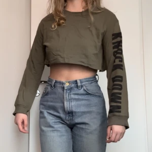 Långärmad Crop-Top - Olivgrön, ångärmad crop top från H&M med svart tryck på ärmen.  - Cool Streetwear stil men tyvärr inte helt min grej längre.