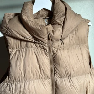 Väst - Beige väst från Cubus i storlek M, passar även L. Med avtagbar luva, sista bilden vänster sida är med luva och höger utan. Inte skrynklig som på bilden när man har på sig den och den har fått ”puffa upp sig lite” då den har varit vakuumförpackad. 