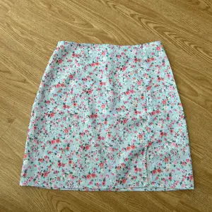 Blå blommig kort kjol med en liten slits i fram och dragkedja i bak. I mycket fint skick, älskar den men är tyvärr för liten för mig. 