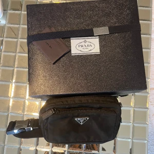 Prada Väska - Prada Belt Bag, bra skick, har legat i garderoben länge så lite dammig på bilderna men det försvinner direkt. Har kvar box, cert osv, tror tyvärr jag tappat bort kvitto. Nypris 15k+, pris ej hugget i sten