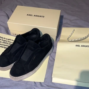 Axel Arigato skor - Säljer dessa Axel Arigato skor i svart. Skorna är väldigt använda och därav har sulan blivit gul, men går ju att fixa om man lägger ner lite tid på att tvätta. Finns även 2 väldigt små hål på insidan vid hälen. Strl 43