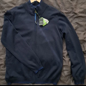 Hugo Boss zip tröja - Hugo Boss, helt ny med prislappen kvar endast testad. Tyvärr för liten. Storlek XL men passar en L bättre. Nypris 1699kr, säljes för 999kr då den är helt ny!  