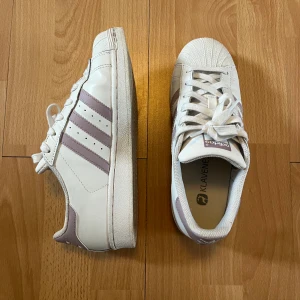 Adidas Superstars - Ett par fina superstars som inte säljs längre. De har en ljuslila nästan lite rosa färg på stripesen och är i jättefint skick. Pris kan diskuteras
