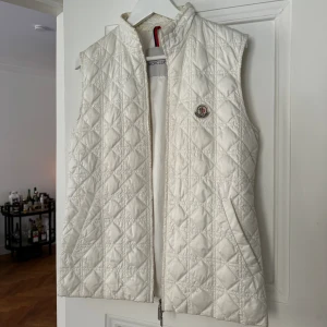 Moncler väst  - Säljer min benvita Moncler väst som inte längre kommer till användning i storlek 2.   Mitt pris: 3000kr