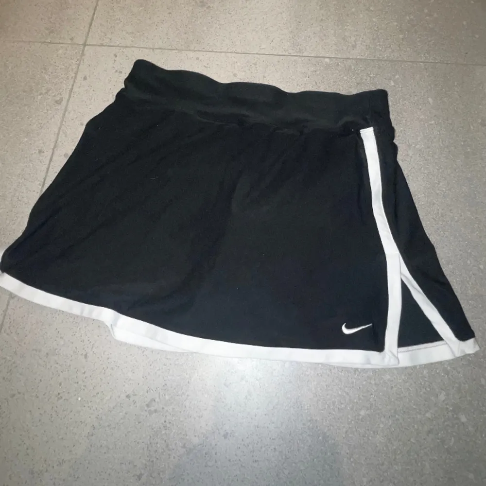 Svart tenniskjol från Nike med vita detaljer, integrerade shorts på insidan, storlek XS 🫶🏼. Kjolar.