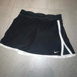 Svart tenniskjol från Nike med vita detaljer, integrerade shorts på insidan, storlek XS 🫶🏼