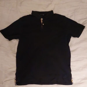 Aquascutum piké - Aquascutum piké i skicket 8/10 använd några gånger, nästan som ny. Svart piké med beigea detaljer likt Burberry.