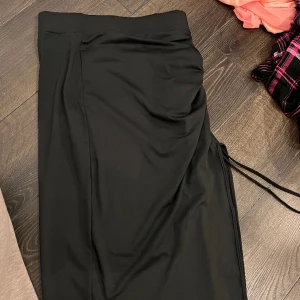 Svart kjol - En svart kjol som man knyter på sida. Är som en slits på sidan