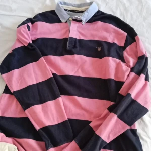 Långärmad collegetröja utan luva - Mörkblå/rosa randig tröja från GANT. Strl 3 XL. 3Knappar vid halsen. Upplevs inte så stor