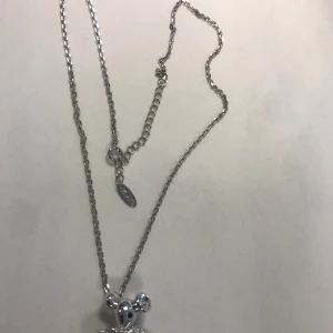 Strass halsband med hängsmycke - Elegant silverfärgat halsband med ett vackert hängsmycke. Kedjan är tunn och smidig, perfekt för att bära till olika tillfällen. Hängsmycket har en glittrig detalj som ger en extra touch av elegans.  Helt ny 