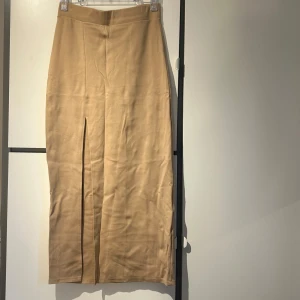 Beige sätt med långkjol och tröja - Snygg beige långkjol med en slits med en kortare topp. Kjolen har en enkel desig det har även toppen.