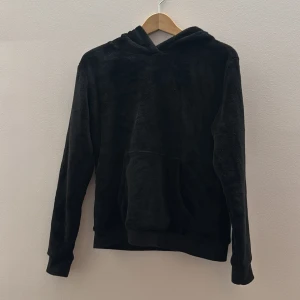 Svart hoodie med drakdetaljer - Mysig svart hoodie med drakdetaljer på huvan. Huvan har gröna ögon och små horn, vilket ger en unik look. Perfekt för dig som vill ha något annorlunda och bekvämt. är i storlek 170