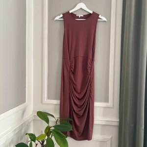 Mörkrosa klänning från Antistar - Snygg mörkrosa partyklänning från Antistar med draperad design och slits i storlek M. Mjukt material. Aldrig använd! 