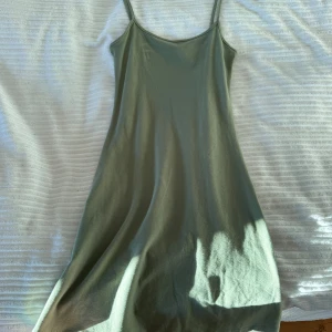 Grön klänning från hm - Säljer en stilren grön klänning från hm i storlek S. Klänningen har smala axelband och en enkel design som passar perfekt för varma dagar. Materialet känns mjukt och bekvämt mot huden.