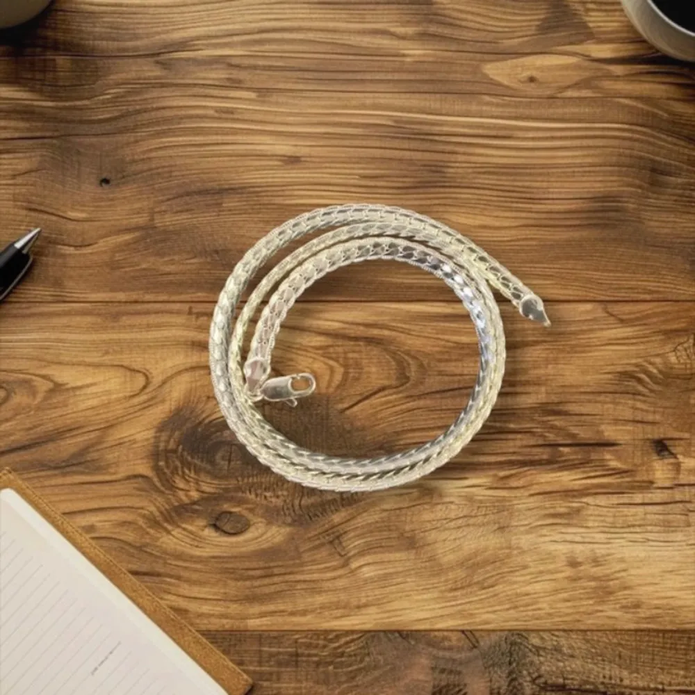 Elegant silverhalsband pläterade med en vacker flätad design. Halsbandet har en karbinhake med stämpeln 925, vilket indikerar äkta silver. Perfekt för att ge en stilren touch till din outfit. 51 cm, 20 gram. Asusteet.