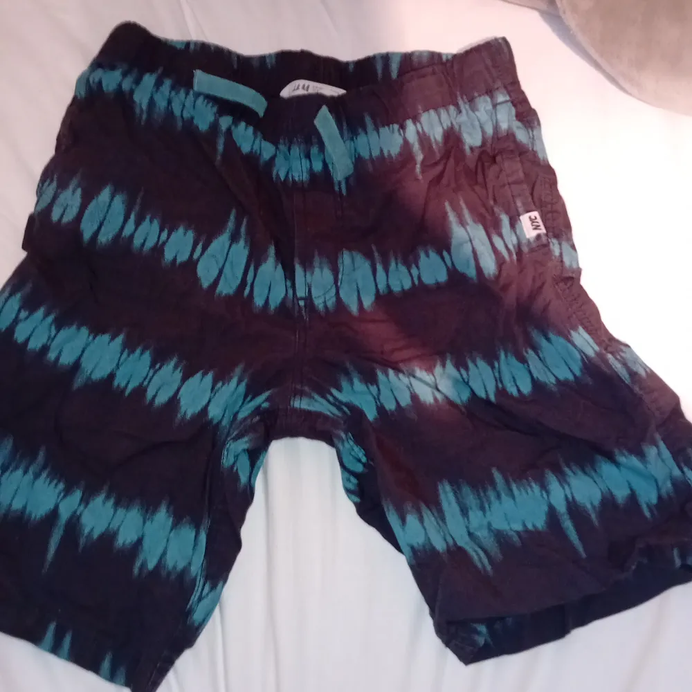 Coola shorts från H&M med ett svart och turkost batikmönster. Perfekta för sommarens äventyr. De har en elastisk midja för extra komfort.. Shortsit.