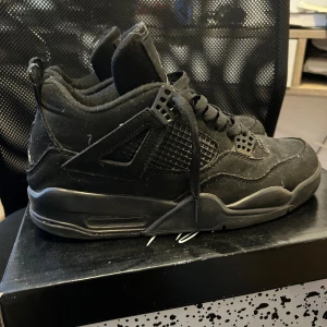 Svarta Air Jordan 4 Retro - Säljer ett par svarta Air Jordan 4 Retro sneakers. Skorna har en klassisk design med snörning och är tillverkade i syntetmaterial. Perfekta för dig som älskar stilrena och ikoniska sneakers. Priset kan diskuteras!