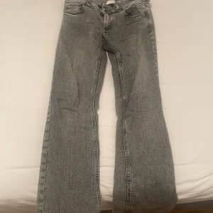 Grå bootcut jeans från H&M - Snygga grå bootcut jeans från H&M med låg midja och justerbar midja. Perfekta för en avslappnad stil med en klassisk bootcut passform. De har fickor både fram och bak.