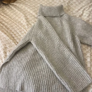 Grå ribbad polotröja - Säljer en mysig grå polotröja med ribbad design. Tröjan har långa ärmar och en hög krage som håller dig varm under kyliga dagar. Perfekt för höst och vinter!