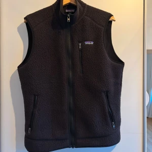 Svart fleeceväst från Patagonia - Säljer en svart fleeceväst från Patagonia med dragkedja framtill. Storlek M och skicket är som nytt. Köpt för 1400kr och säljer för 850kr. Två praktiska fickor med dragkedjor. Tveka inte skicka ett meddelande om du har frågor eller är intresserad.