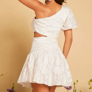 Vit oneshoulder klänning - Vit oneshoulder klänning med cut-out detalj i midjan. Perfekt för sommaren och studenten! Aldrig använd! Nypris 290 kr