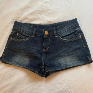 Lågmidjade jeansshorts från Gina tricot - Snygga mörkblå jeansshorts från Perfect Jeans/Gina Tricot med klassisk femficksdesign och knappgylf. Storlek 34 och passar xs och s. Säljer då de blivit för små för mig. 