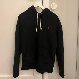 Svart hoodie från Polo Ralph Lauren - Säljer en stilren svart hoodie från Polo Ralph Lauren med en ficka där fram. Hoodien är i bra skick. Storlek M. Köptes för cirka 1800 kronor. 