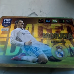 FIFA 365 Limited Edition Morata Kort - Säljer ett FIFA 365 Limited Edition samlarkort med Morata i Real Madrid-tröja. Kortet har en glänsande yta och visar spelaren i en actionpose. Perfekt för samlare av fotbollskort!