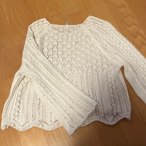 Vit stickad tröja från ONLY - Säljer en vit stickad tröja från ONLY med ett vackert spetsmönster. Tröjan har långa ärmar och en lös passform, perfekt för en avslappnad stil. Den är både stilren och bekväm.