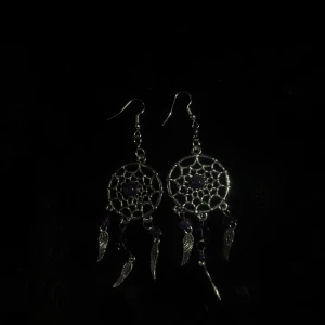 Silvriga drömfångarörhängen med fjädrar - Handgjorda örhängen i form av drömfångare med detaljerade fjädrar och små lila pärlor. Perfekta för att ge en vibe touch till din stil. Tillverkade i silverfärgat material med krokfäste.