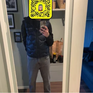 Svart dunväst från Peak Performance - Säljer en snygg mörkblå dunväst från Peak Performance. Västen har en dragkedja framtill och är perfekt för kyligare dagar. Den är stilren och lätt att matcha med olika outfits. Passar bra för både vardag och utomhusaktiviteter. Har ett litet lagat hål, men syns inte när västen används