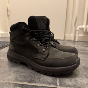 Svarta kängor från Helly Hansen - Säljer ett par robusta svarta kängor från Helly Hansen i bra skick. Perfekta för höst och vinter med slitstark snörning och bekväm passform. De är gjorda i skinn och har en stabil sula som ger bra grepp på hala underlag. Perfekta för både stad och natur! Köptes i vinter förr året för cirka 1000kr, lite smutsiga på bilden men går lätt att ta bort!