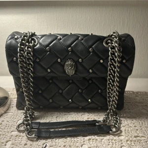 Svart axelväska med kedja och nitar - Snygg väska med coola detaljer! Medium modell, så ganska rymlig! Fint skick både inne och ute. Köpt för ca 2 år sedan nypris 3500