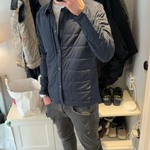Mörkblå quiltad jacka från J.Lindeberg - Säljer en snygg mörkblå quiltad jacka från J.lindeberg. Perfekt för höst och vår, med en stilren look som passar både till vardags och lite finare tillfällen. Den är i mycket bra skick och redo för en ny ägare! Ny pris: 2300