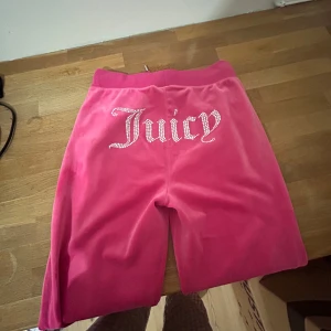 Rosa velourbyxor från Juicy Couture - Säljer ett par superbekväma rosa velourbyxor från Juicy Couture. Baktill finns texten 'Juicy' i glittriga stenar. Användes några få gånger, fick små fläckar på nedre delen som går att tvättas bort